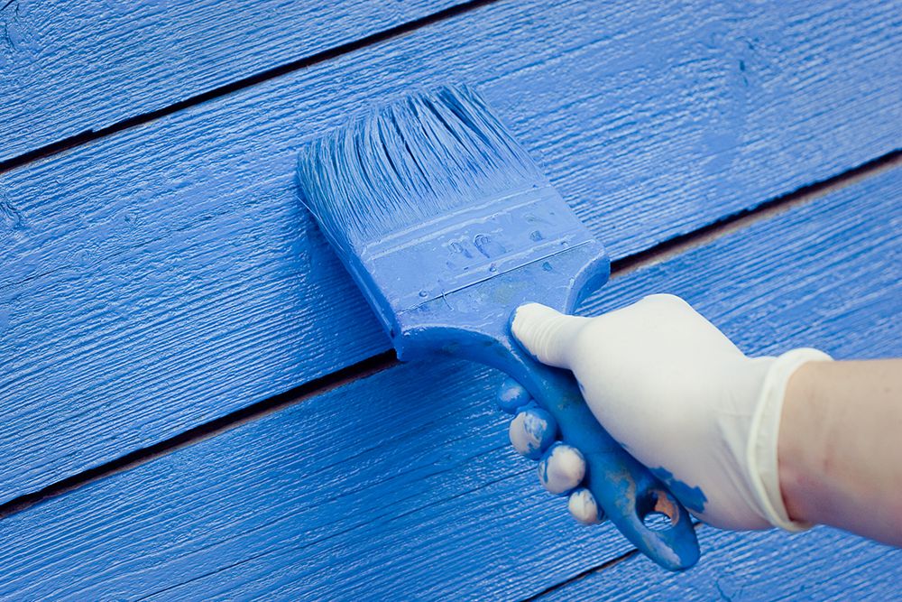 Maler streicht Holz mit blauer Farbe